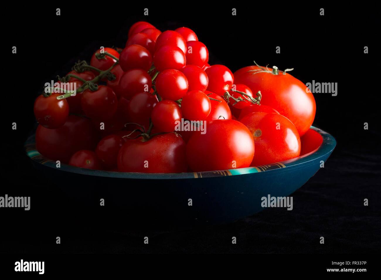 Ein low-Key dramatisches Bild einer Schüssel Tomaten auf einem schwarzen Hintergrund Stockfoto