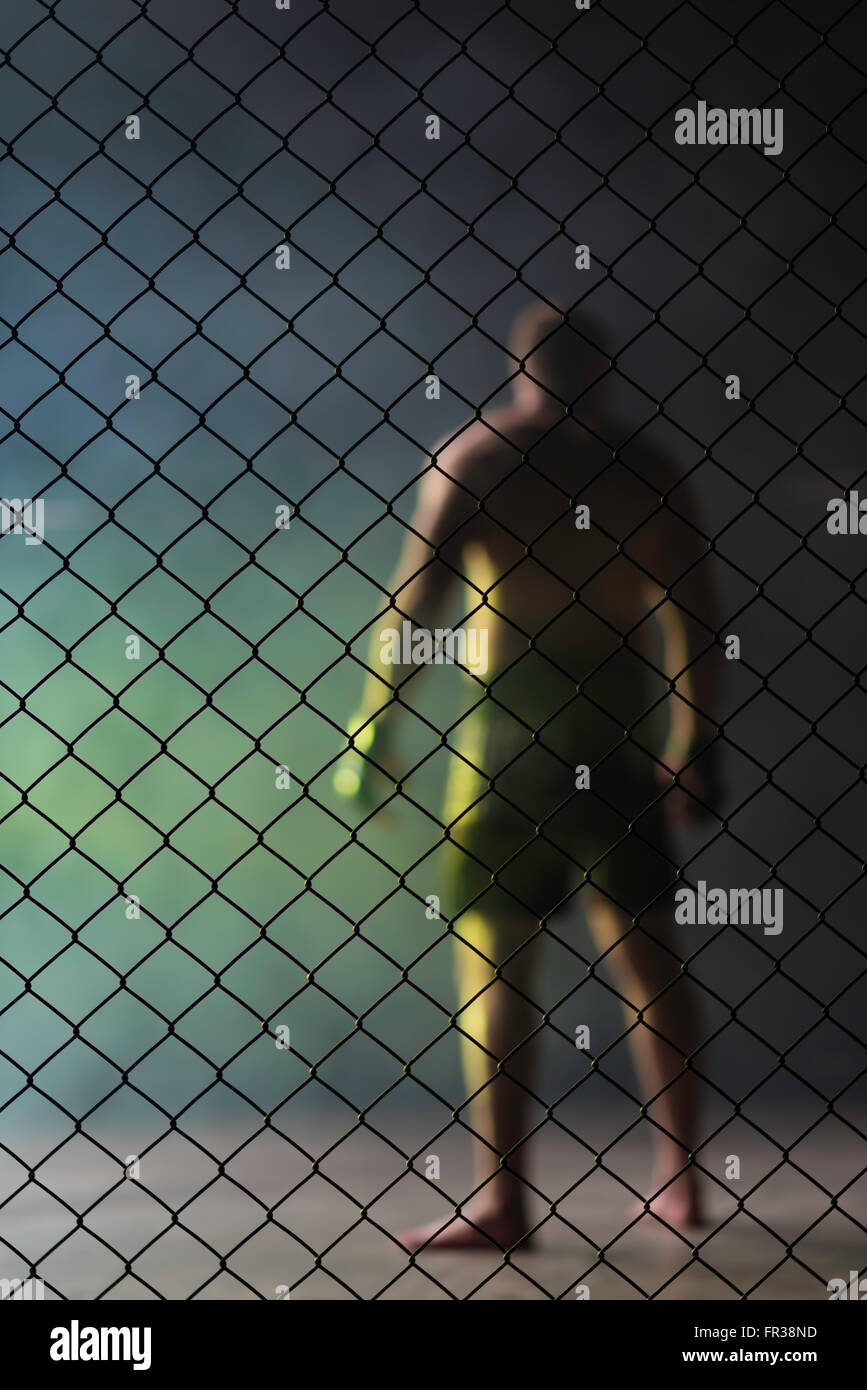 Ein Kämpfer steht im Rauch in einem Käfig vor dem Kampf. Stockfoto