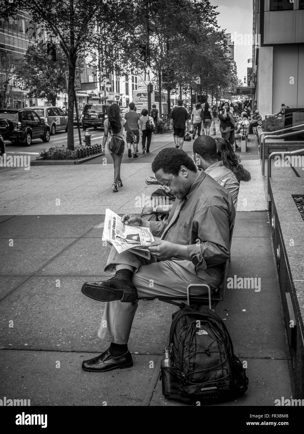 Geschäftsmann saß auf der Bank und im freien liest Zeitung, New York City, USA. Stockfoto