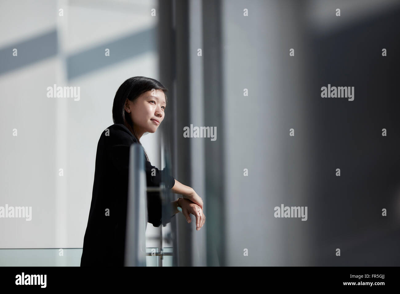 Nachdenklicher Blick durch sonnige Bürofenster Geschäftsfrau Stockfoto