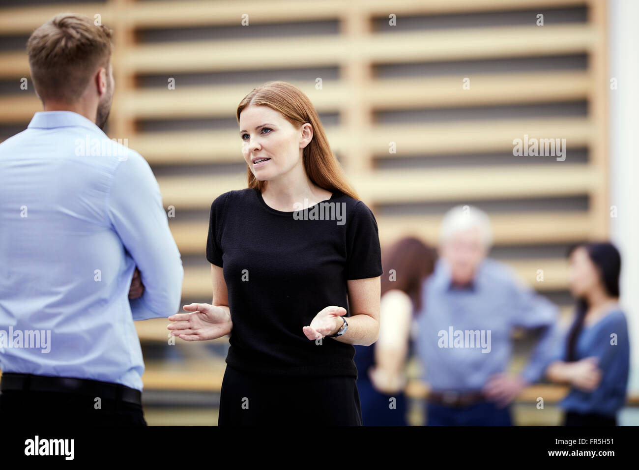 Geschäftsfrau, gestikulieren und im Gespräch mit Geschäftsmann in lobby Stockfoto