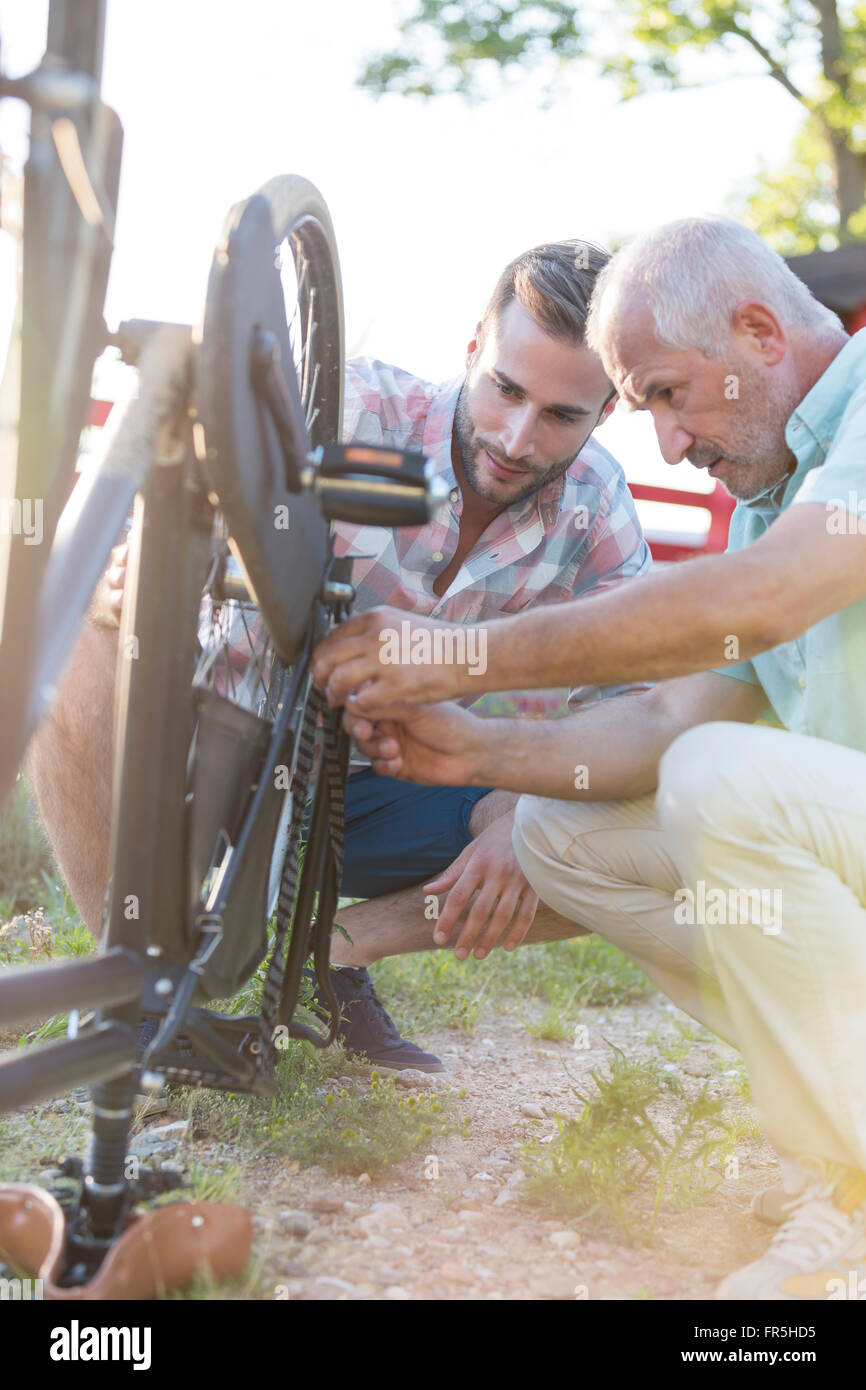 Vater und erwachsener Sohn Reparatur Fahrrad-Kette Stockfoto