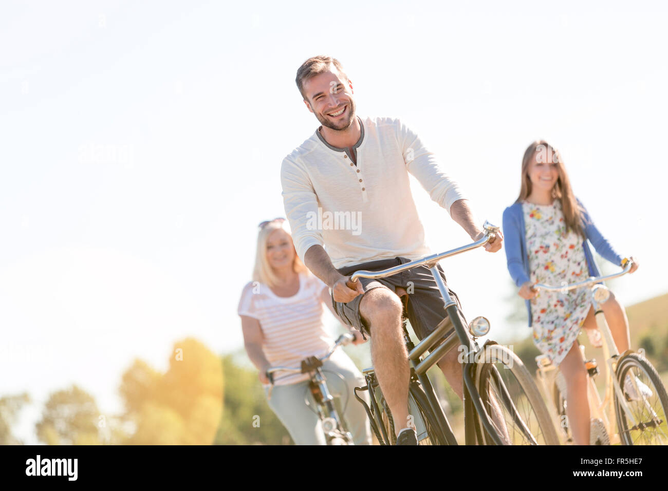 Lächelnd junger Mann Radfahren mit Frauen Stockfoto