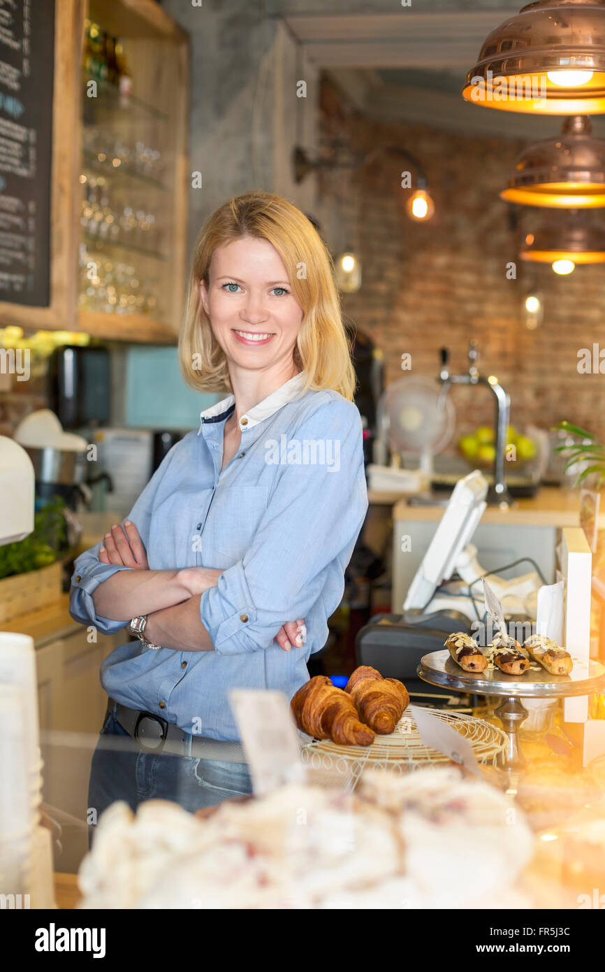 Porträt lächelnd Café-Besitzer mit Arme gekreuzt hinter der Theke Stockfoto