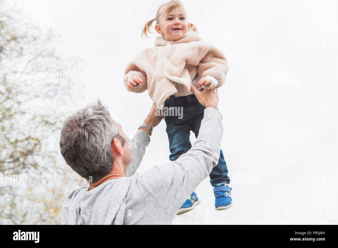 Vater anhebende Kleinkind Tochter overhead Stockfoto