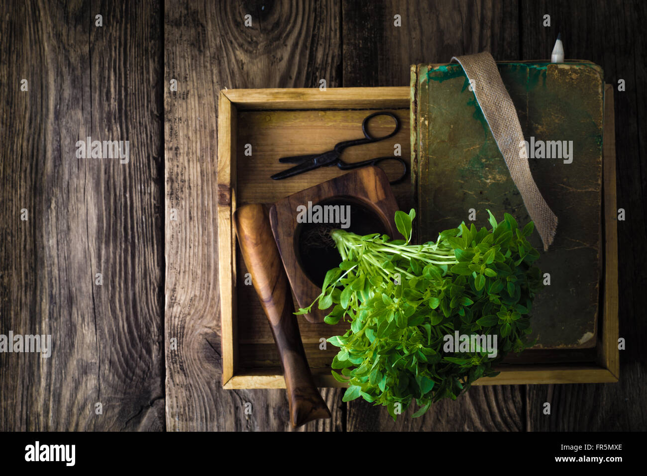 Basilikum, einem Buch und einem Mörser auf einem Holztisch horizontale Stockfoto