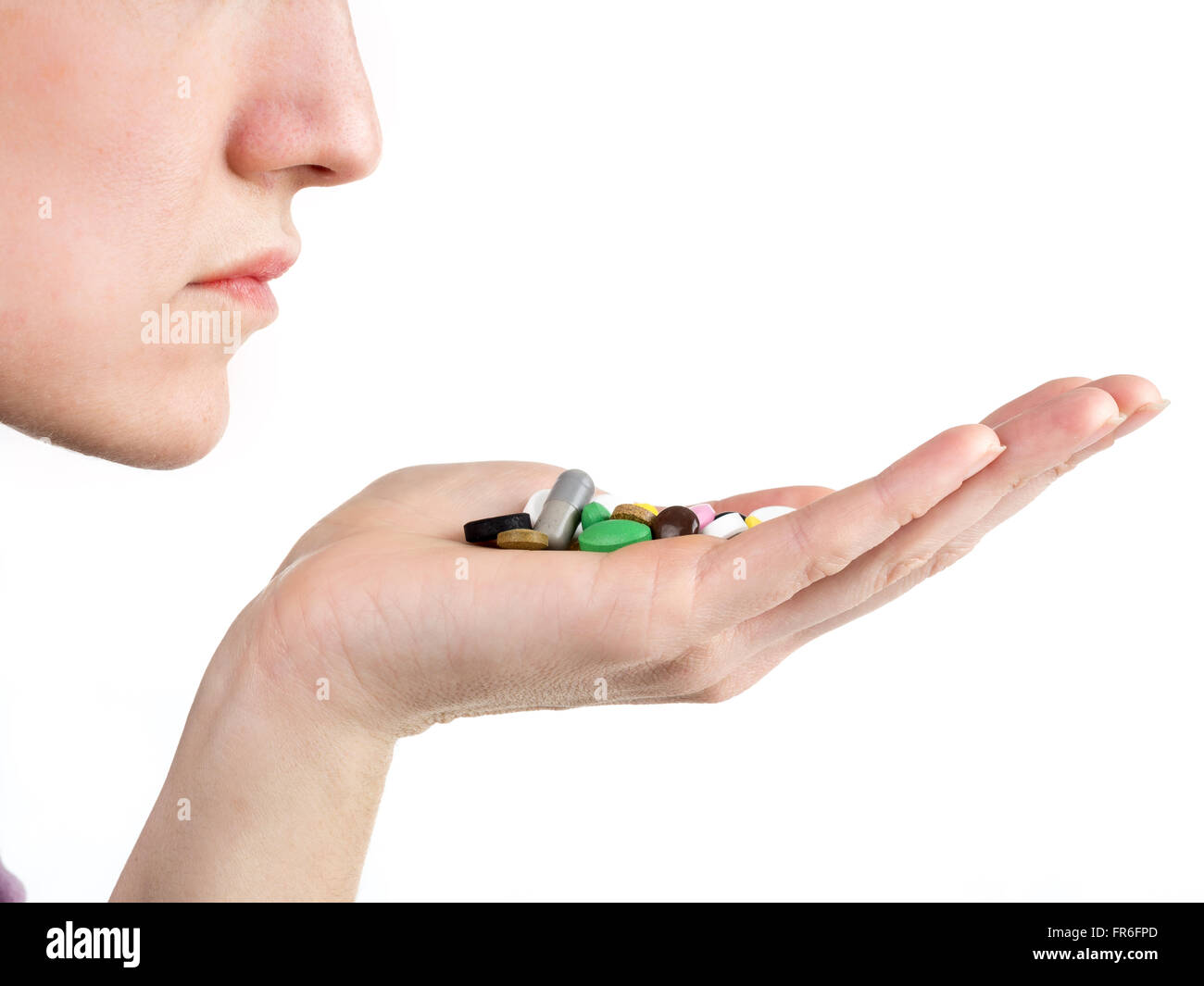 Weibliche Hand hält alle Arten von Pillen und Tabletten in der Nähe von Mund auf weißem Hintergrund Stockfoto
