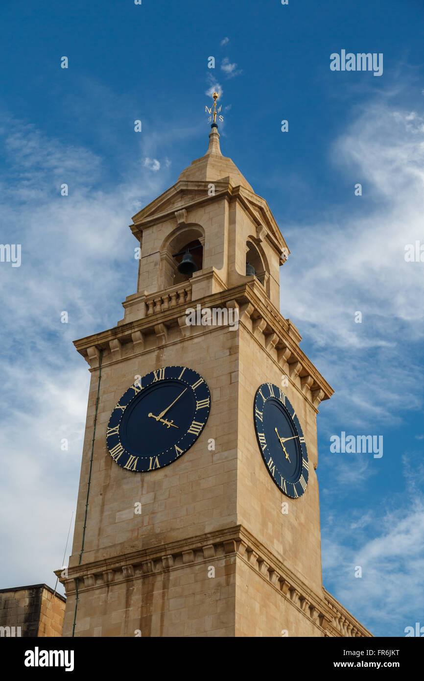 Blick auf eine Kirche in Valletta Malta mit Kalkstein Glockenturm Uhrturm, auf blauen Wolkenhimmel Hintergrund. Stockfoto
