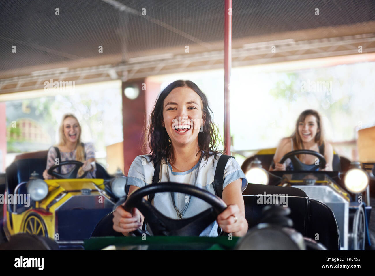 Porträt, lächelnde junge Frau Reiten Autoscooter im Freizeitpark Stockfoto