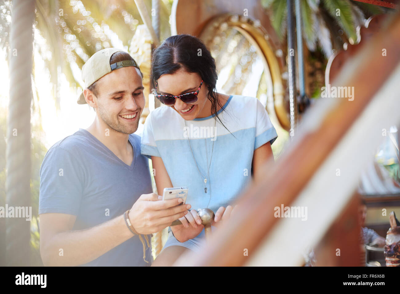 Junges Paar SMS mit Handy im Freizeitpark Stockfoto