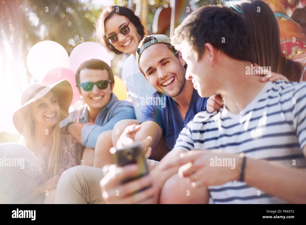 Lächelnden Freunde SMS mit Handy im Freizeitpark Stockfoto