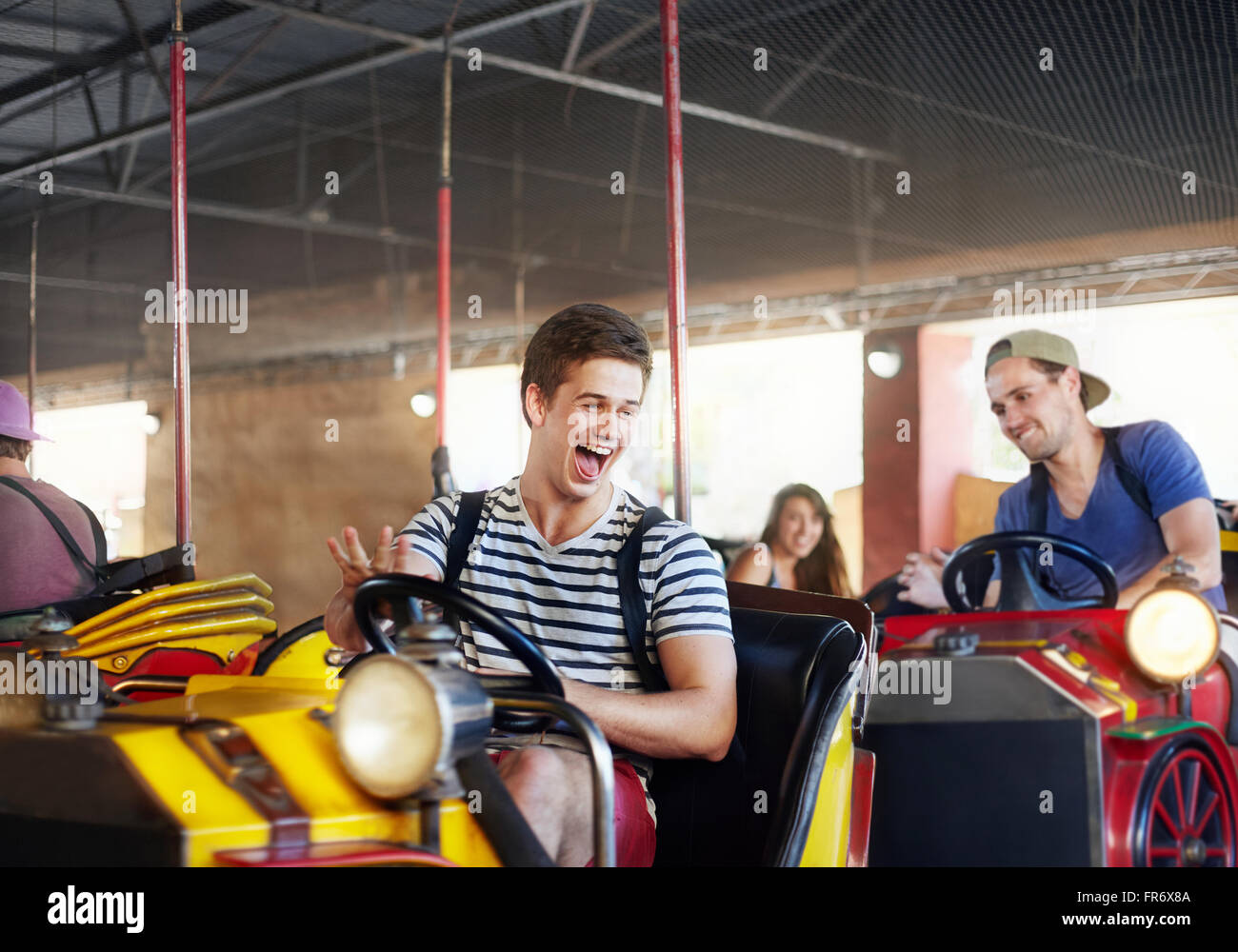 Junge Männer reiten Autoscooter im Freizeitpark lachen Stockfoto