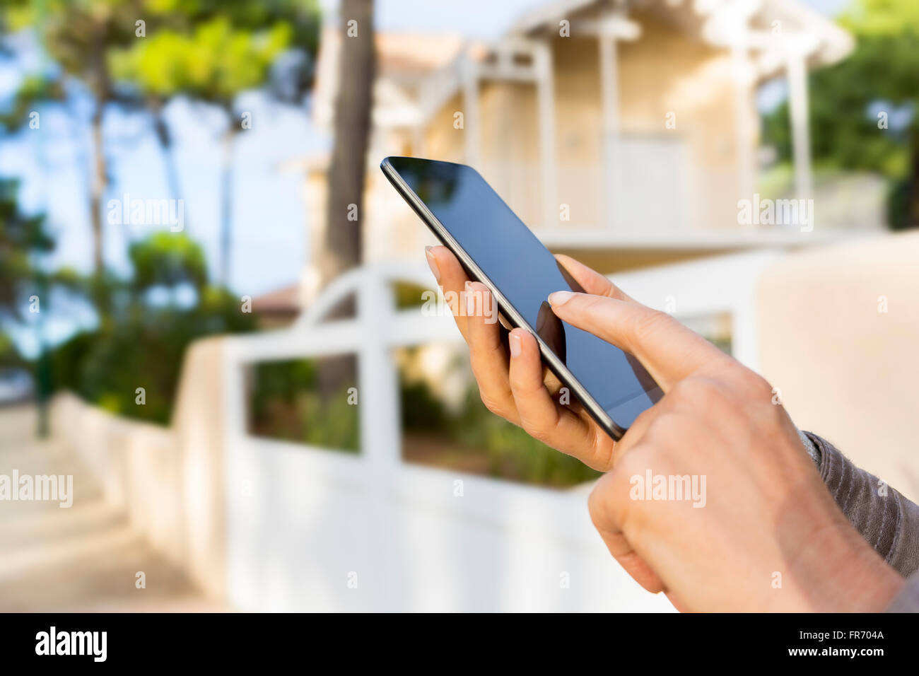 In der Straße Frau mit Handy Anwendung. Schönes Haus Hintergrund weichzeichnen Stockfoto