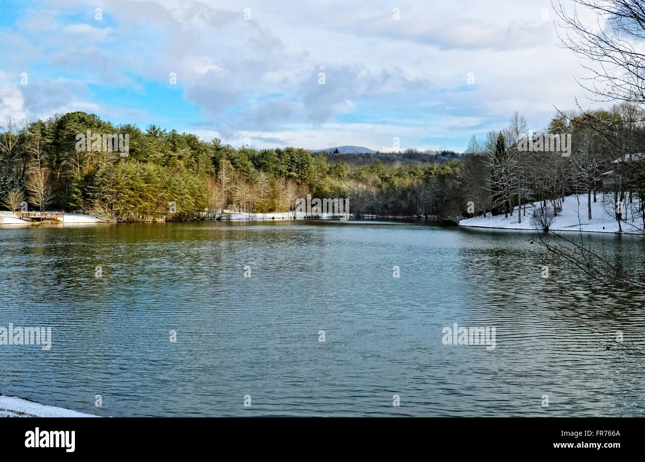 Ein kleiner See mit einer leichten Prise Schnee und Berge in der Ferne. Stockfoto