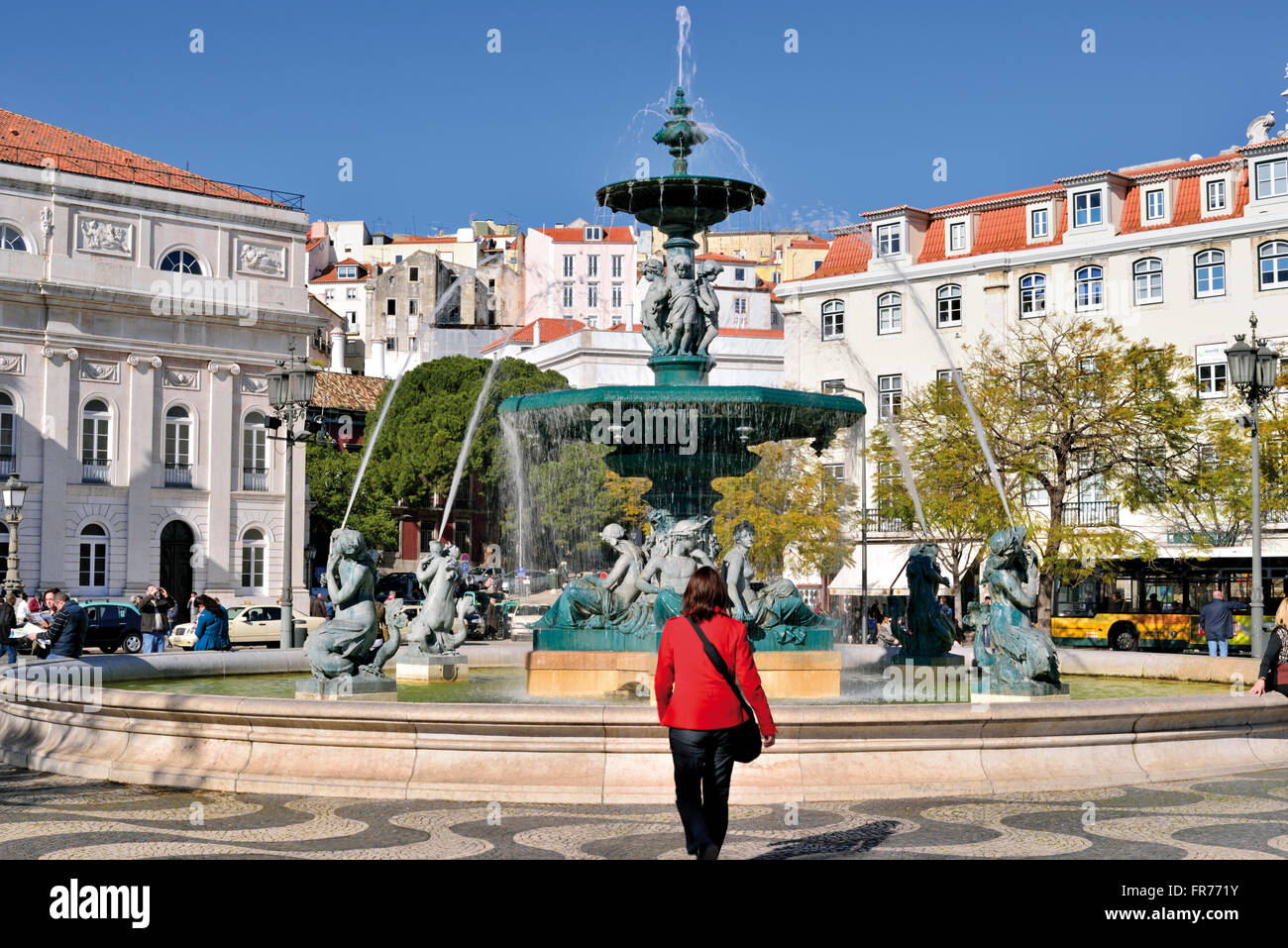 Portugal, Lissabon: Frau mit roter Jacke, die zu Fuß in Richtung ein Brunnen am Rossio Platz Stockfoto