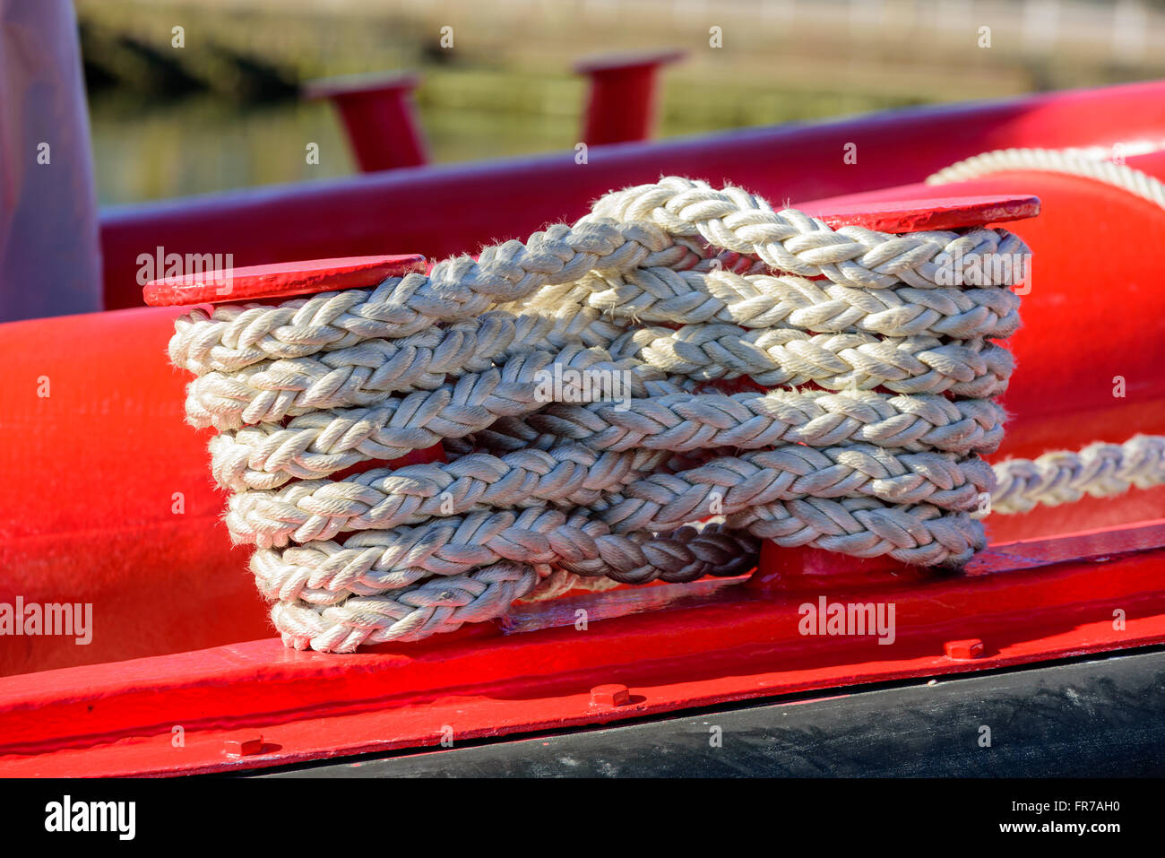 Festmacher Seil verdreht auf einem roten Schiff. Seil ist weiß, aber ein bisschen schmutzig und gut genutzt. Stockfoto