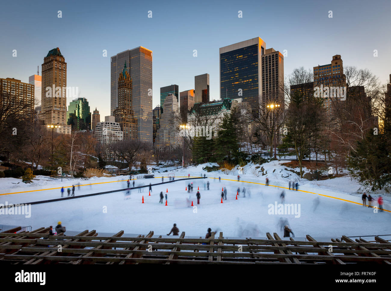 Central Park Eislaufen, Wollman Rink, mit Midtown Manhattan Wolkenkratzer in der Dämmerung. New York City Stockfoto