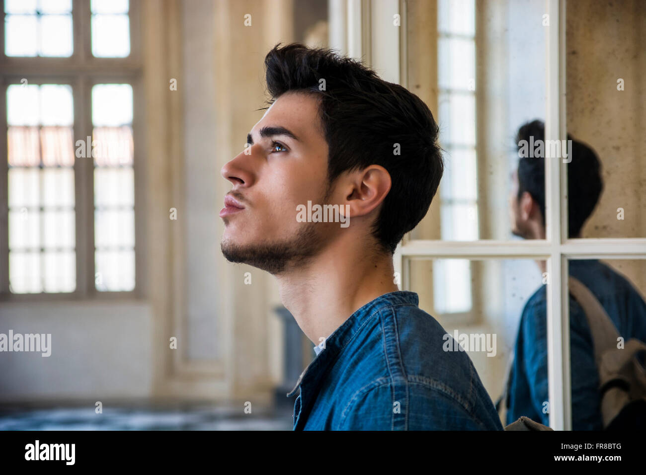 Eine halbe Stelle erschossen einer nachdenklichen hübscher Junge Mann auf der Suche entfernt aus Fenster, innen historisches Gebäude in europäischen Stadt Stockfoto