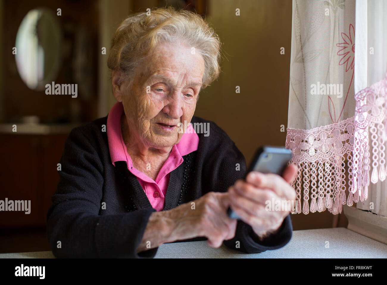 Ältere Frau am Tisch auf einem Smartphone eingeben. Stockfoto