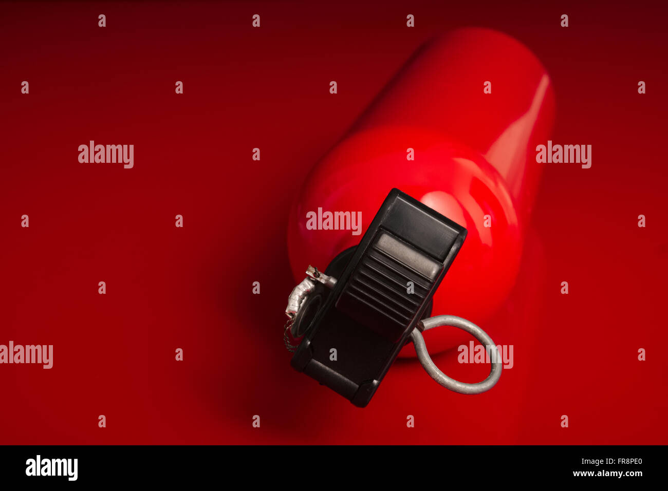 Einen kleinen Feuerlöscher auf eine rote Fläche liegend mit der oberen Düse aus dem Bild zeigen Stockfoto