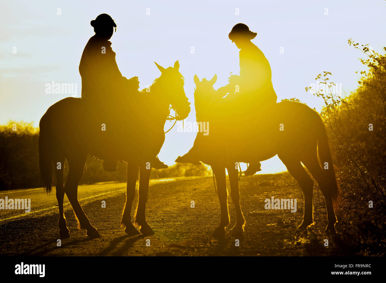 Sonnenuntergang und Cowboys auf dem Weg durch die Savanne Stockfoto