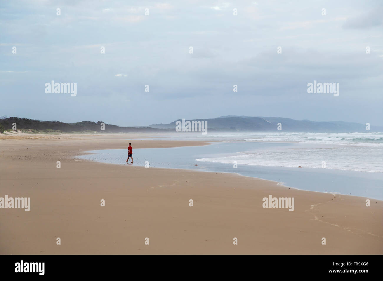 Person geht auf das Wasser am Strand entlang der Nordküste von Schlinge bei bewölktem Himmel; Noosa, Queensland, Australien Stockfoto