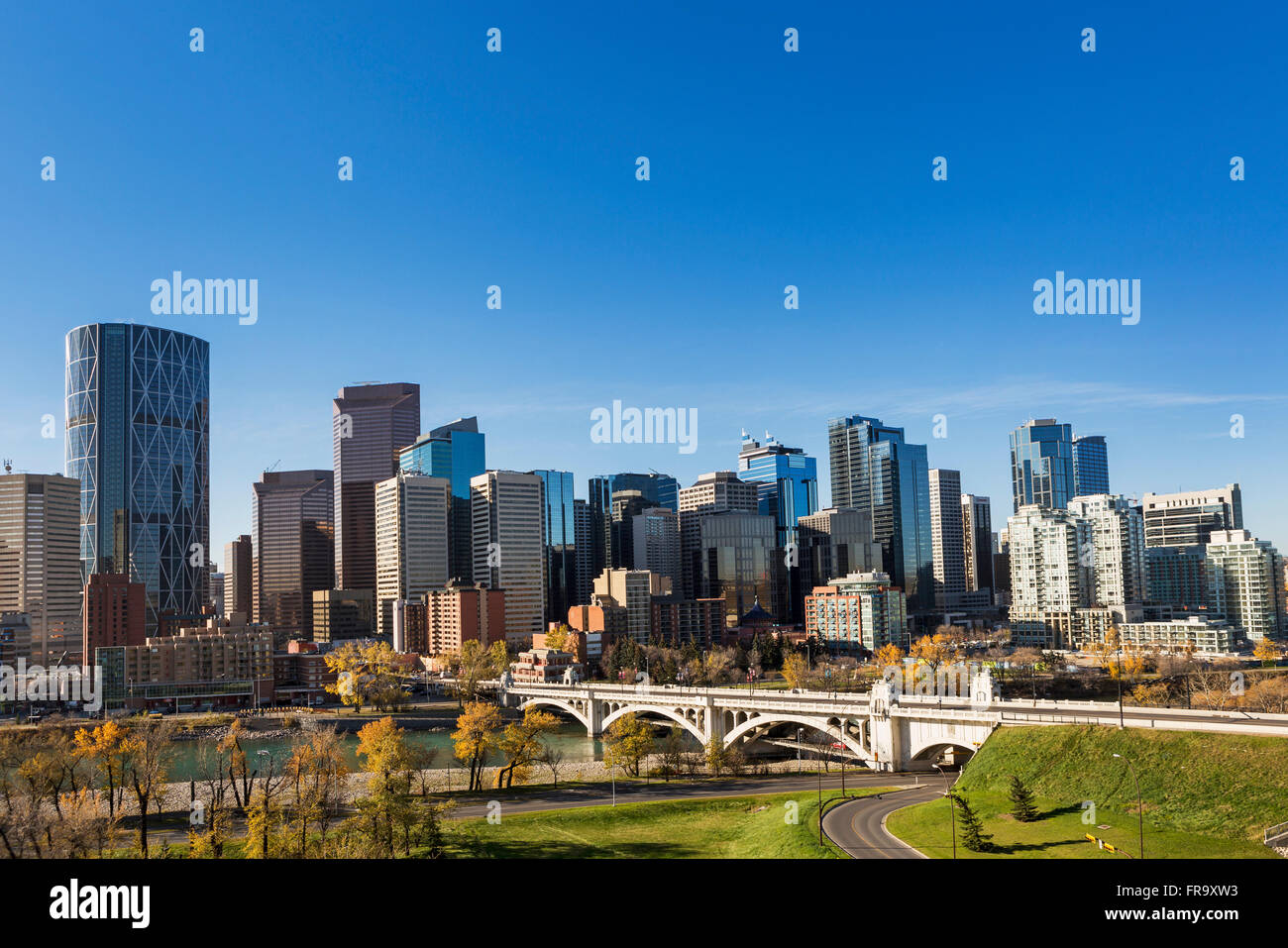 Skyline von Calgary mit Brücke über Fluss, Herbst farbige Bäume und blauer Himmel überspannt; Calgary, Alberta, Kanada Stockfoto