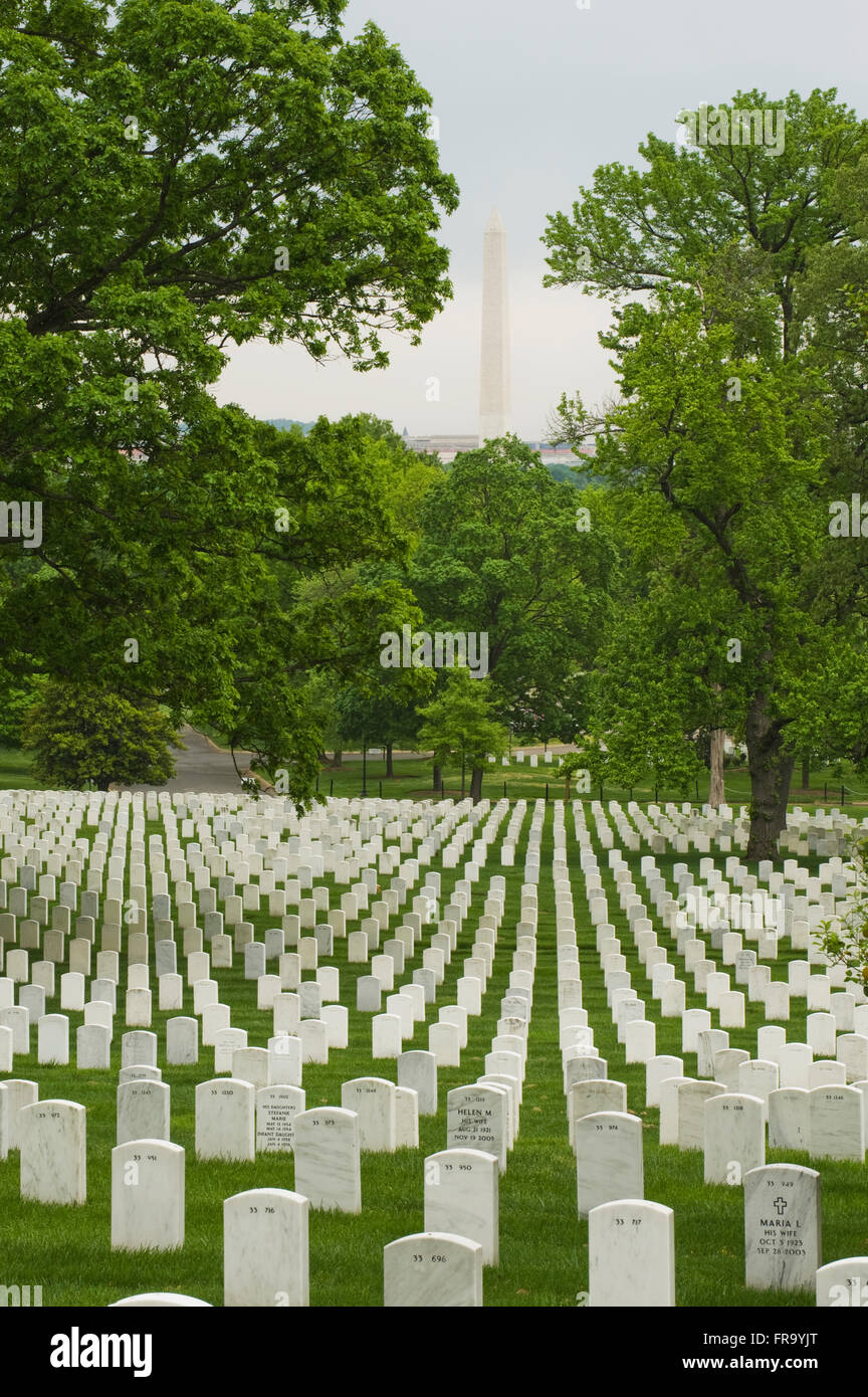 Reihen von Grabsteinen auf dem Nationalfriedhof Arlington, mit dem Washington Monument über den Fluss in Washington, D.C. Stockfoto