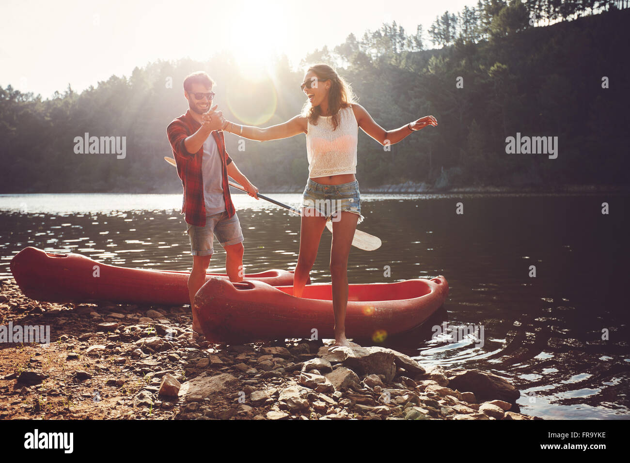 Junger Mann hilft Frau, einen Schritt aus einem Kajak. Paar nach Kajakfahren auf dem See an einem sonnigen Tag. Stockfoto