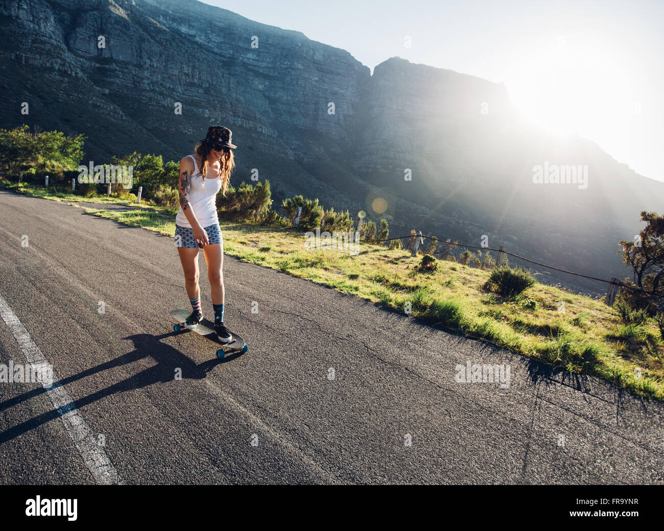 Junge Frau Eislaufen im Freien auf der Landstraße. Weibliche Longboarding an einem Sommertag. Stockfoto