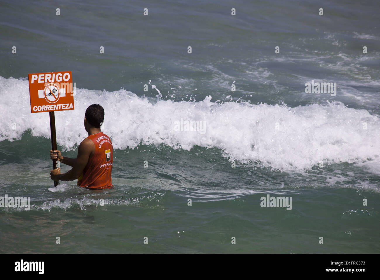 Feuerwehrmann Rettungsschwimmer halten der aktuellen Warnschild am Strand von Ipanema Stockfoto