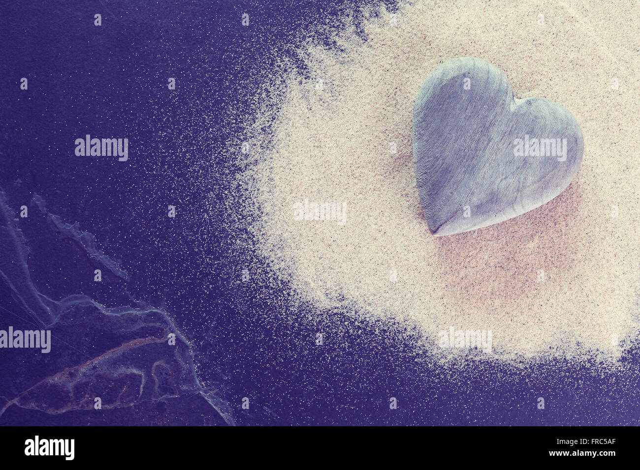 Vintage getönten Herz aus Holz auf Sand und Stein Hintergrund aus gebrochenen Schiefer. Stockfoto