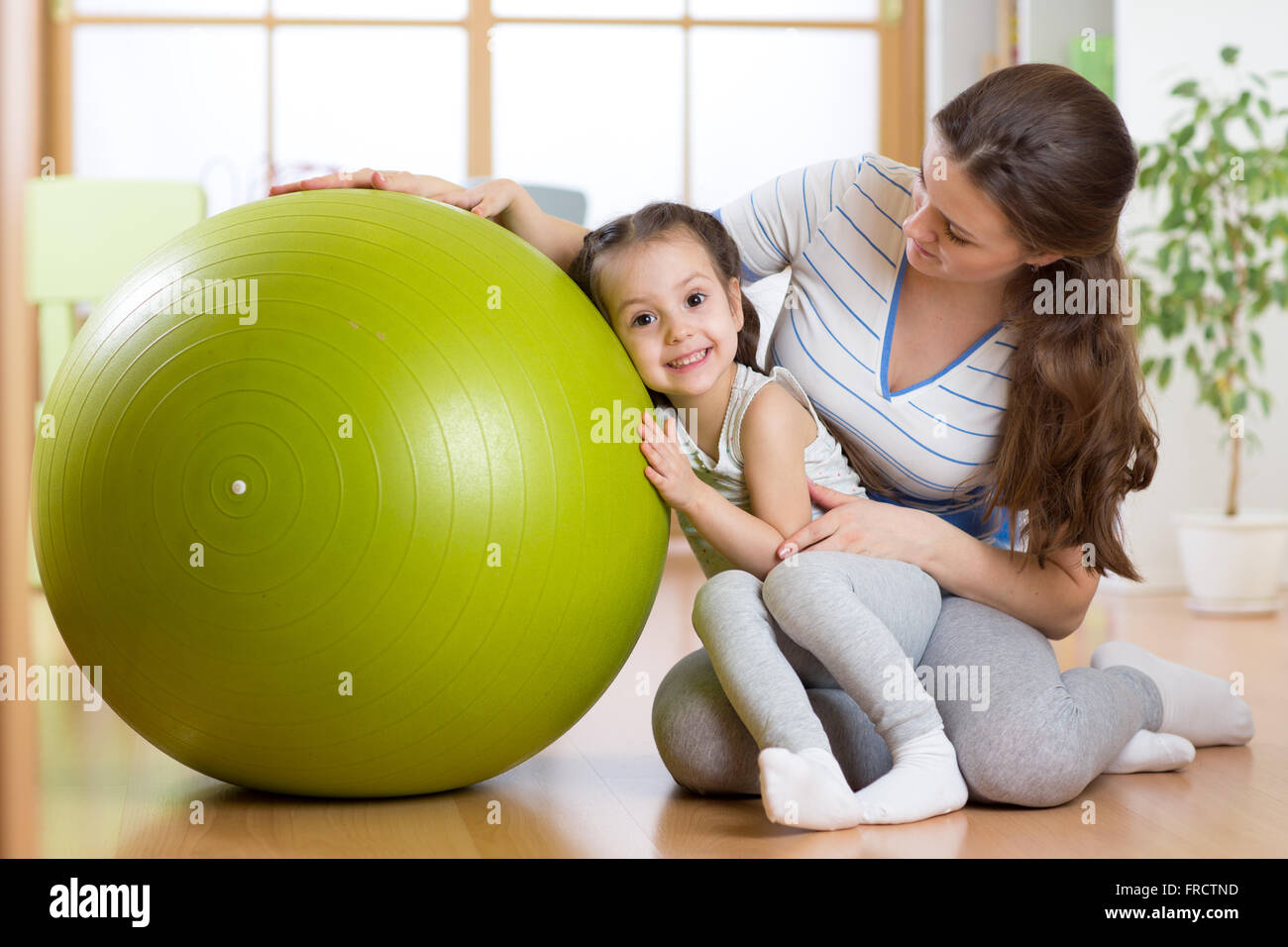 Kind Mädchen und Mutter mit Fitness-Ball indoor Stockfoto