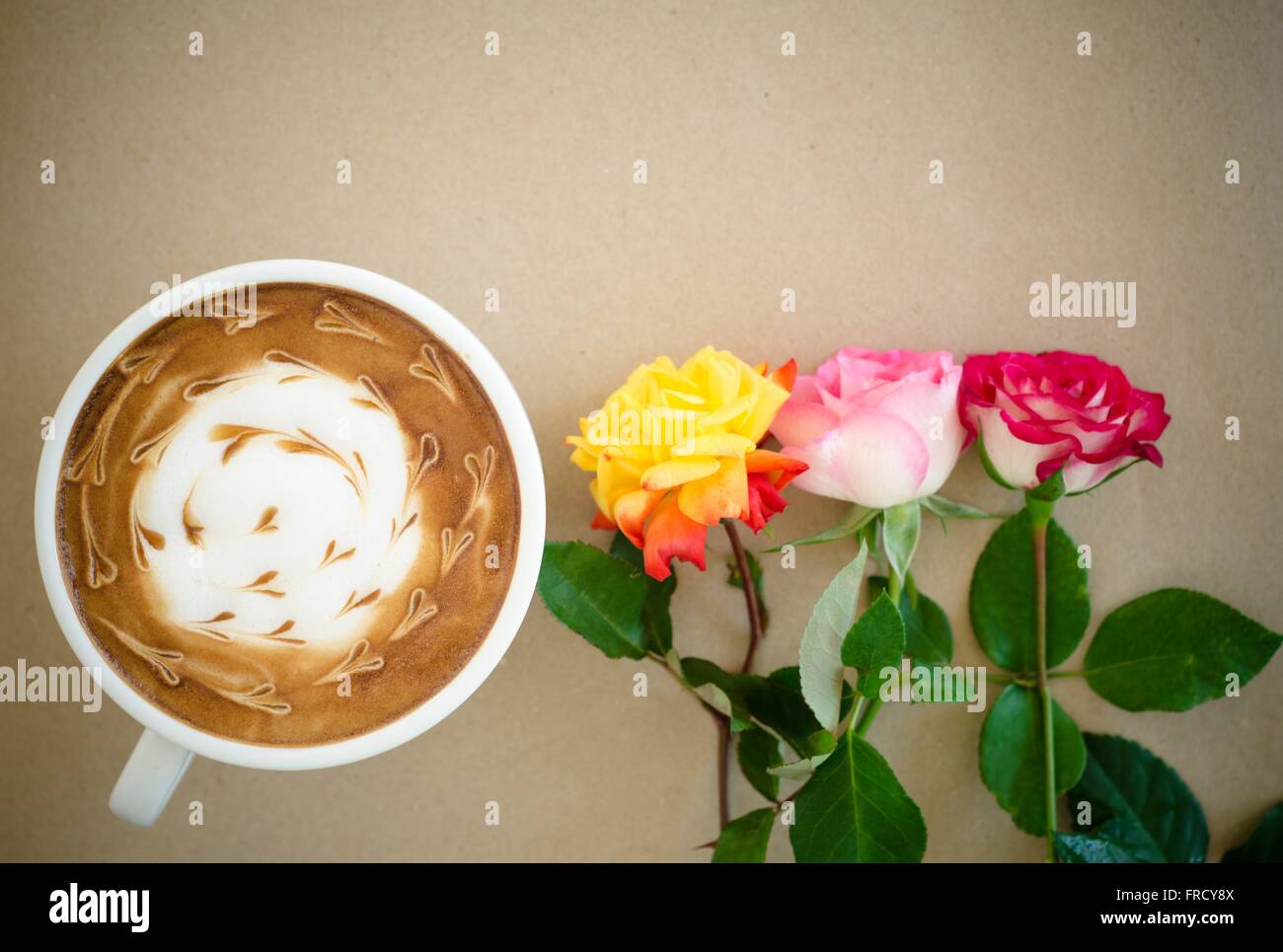 Eine Tasse Kaffee mit Latte Art und Rose auf braunem Papierhintergrund Stockfoto