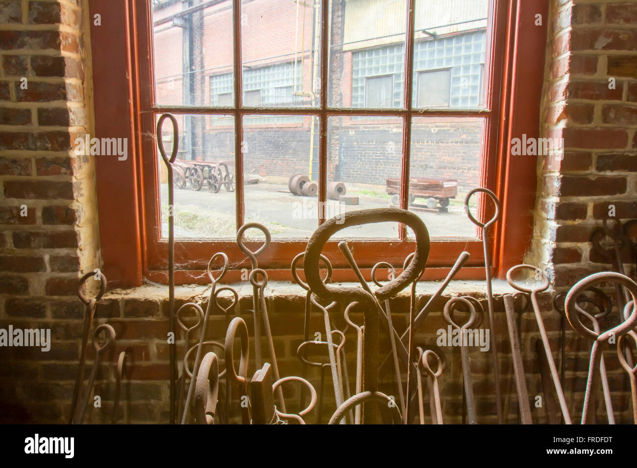 Rostende Werkzeuge gelehnt Fenster mit Spinnweben in Backstein-Schmiede. Stockfoto