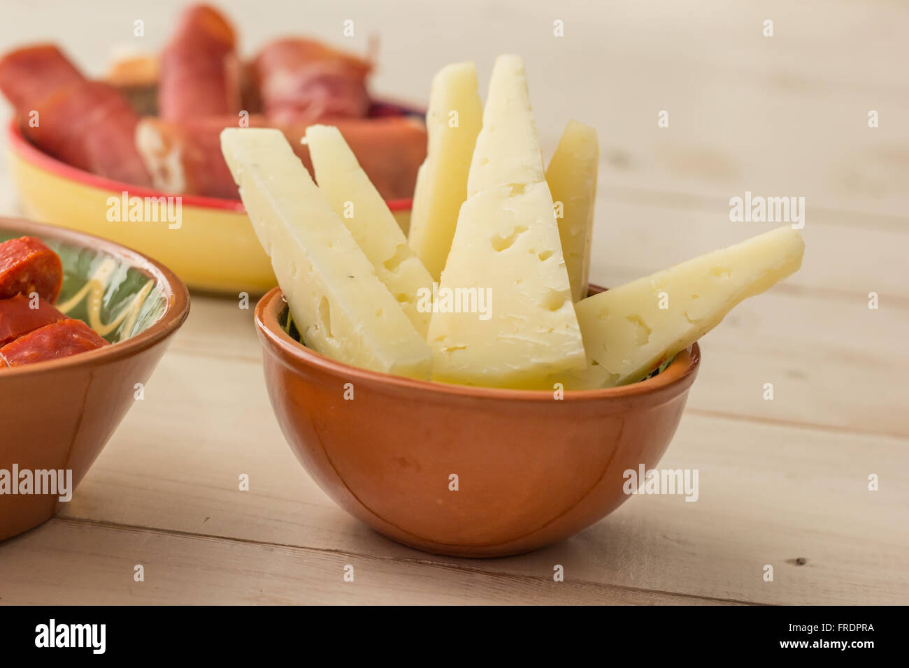 Tapas, Manchego-Käse und Schinken auf einem weißen Tisch Stockfoto