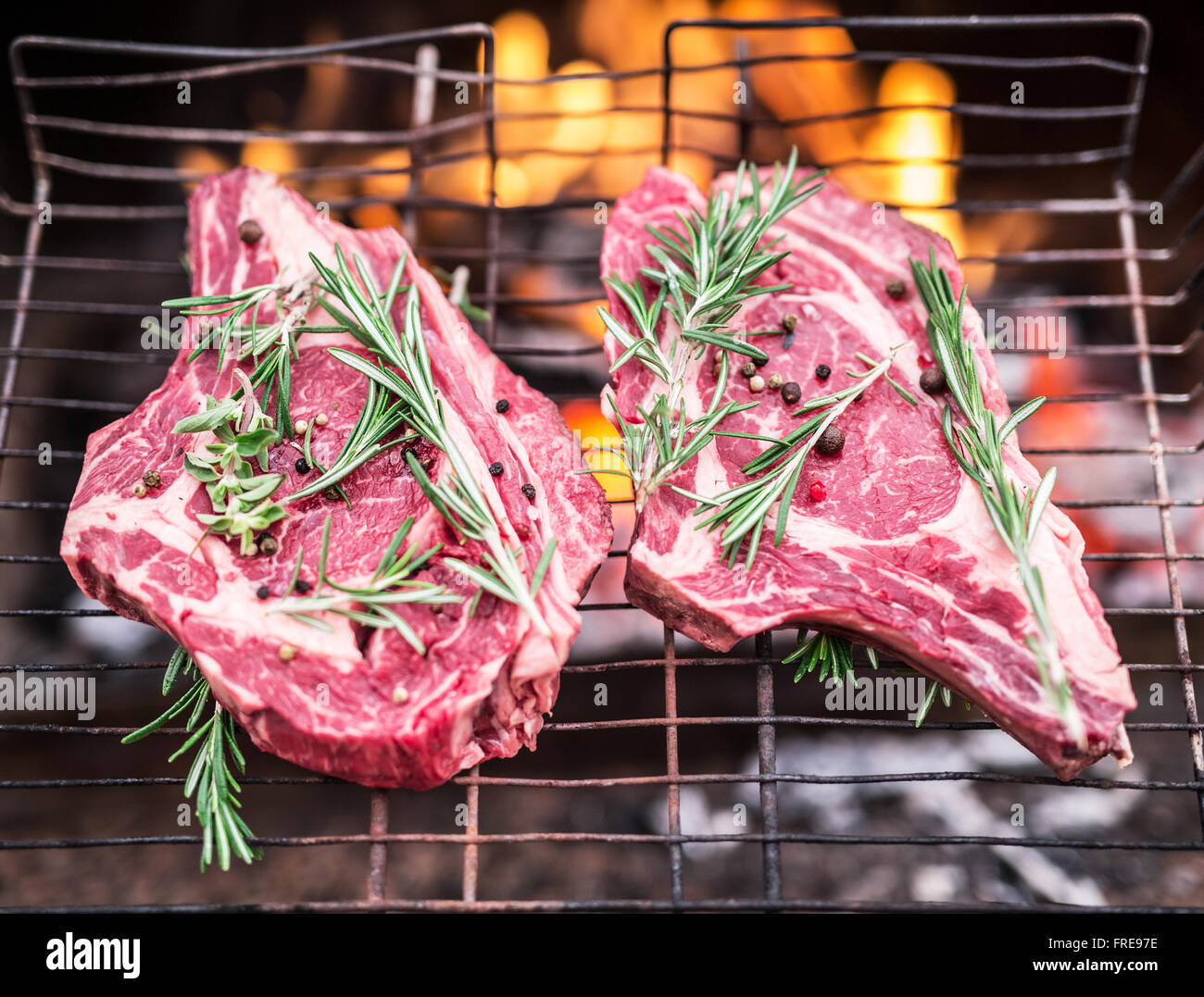 Rib-Eye-Steaks und Grill mit brennendem Feuer hinter ihnen. Stockfoto