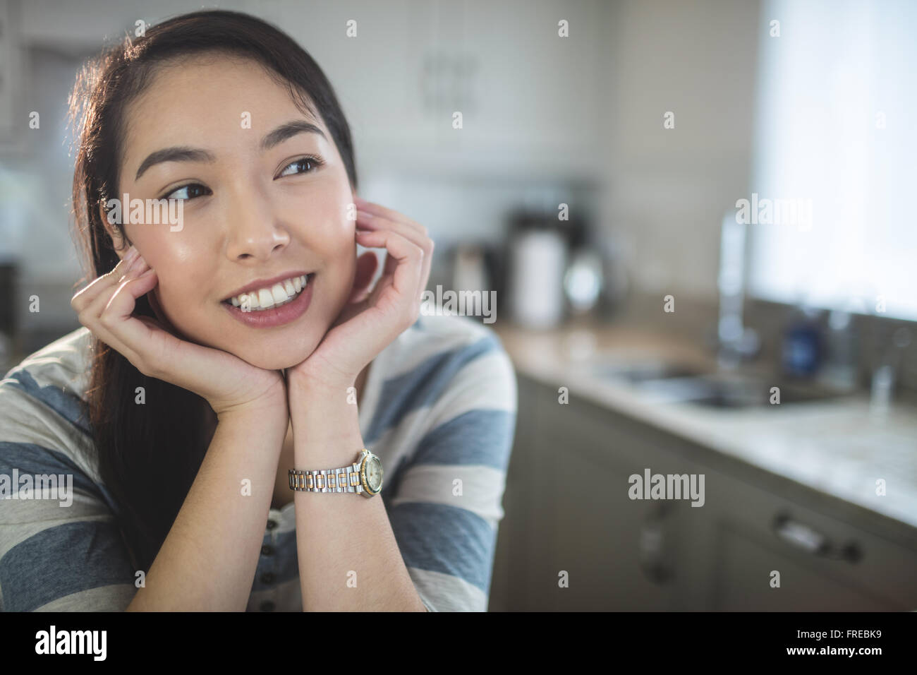 Junge Frau Tagträumen in Küche Stockfoto