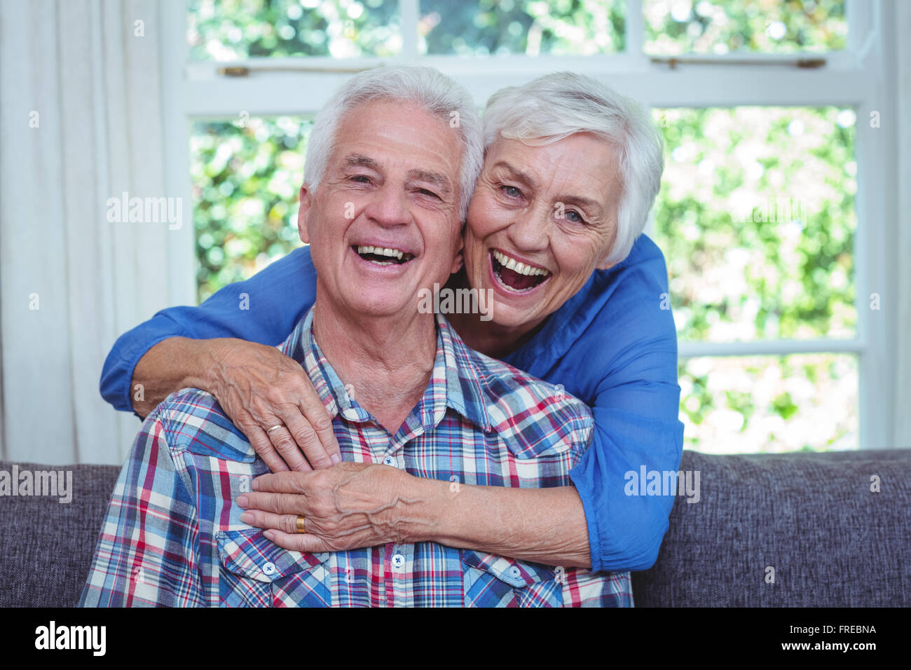 Ältere Frau lachen während umarmen Mann von hinten Stockfoto