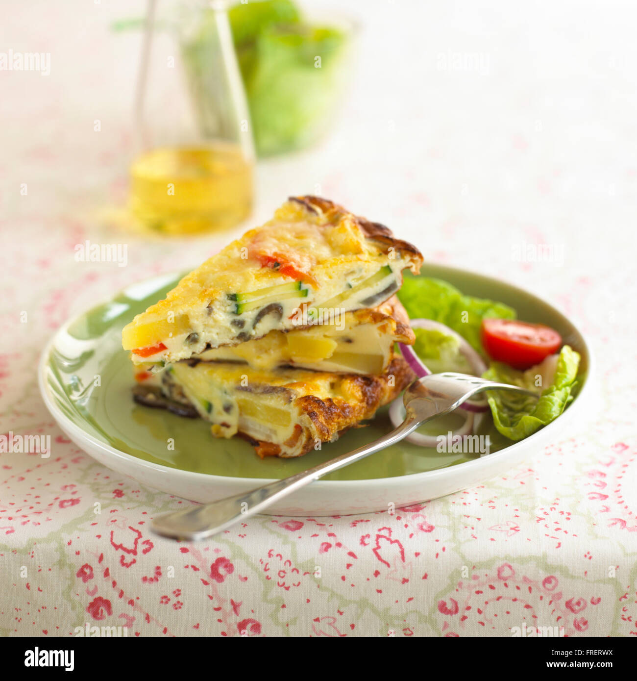 Frittata Provencale, drei Keile Omelette mit Gemüse auf Teller mit Salat und Gabel Stockfoto