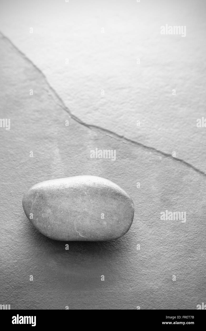 Schwarz / weiß Foto eines Steines auf Schiefer Hintergrund mit Textfreiraum, geringe Schärfentiefe. Stockfoto