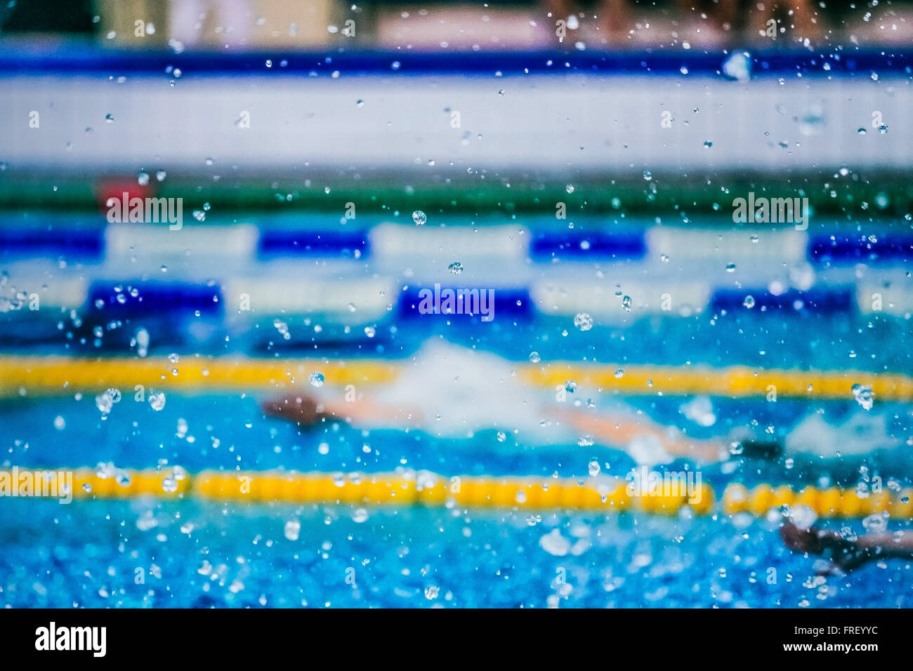 Wassertropfen auf Glaslinse. Unschärfe-Effekt. im Hintergrund Pool und Schwimmer Athlet Stockfoto
