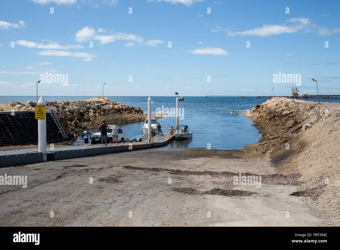 neu gebaute Bootsrampe am Ufer zwischen steinigen Böschungen, Steg im Hintergrund Stockfoto