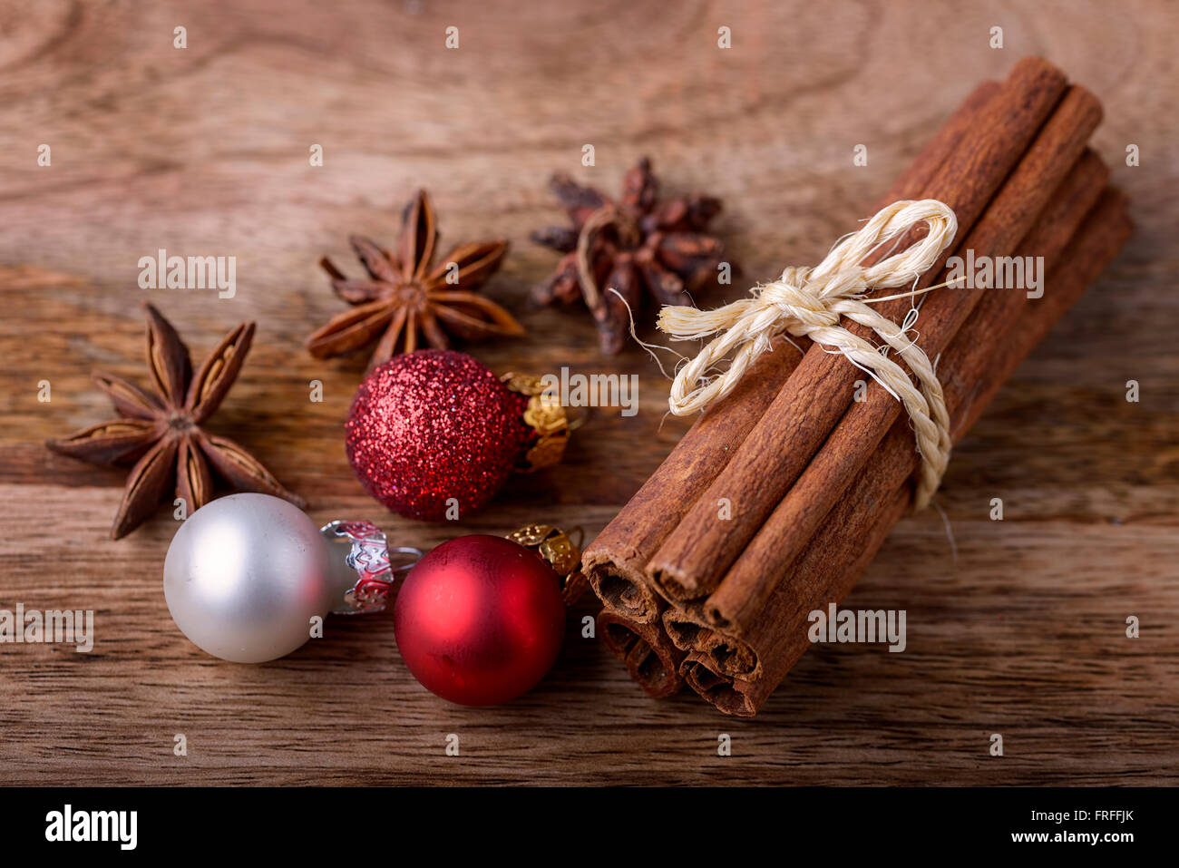 Zimt und Sternanis mit roten und weißen Weihnachtskugeln auf Holz Stockfoto