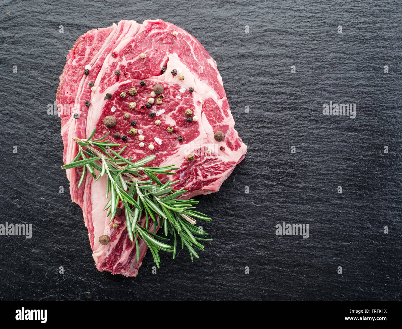 Rib-Eye Steak mit Gewürzen auf dem schwarzen Hintergrund. Stockfoto