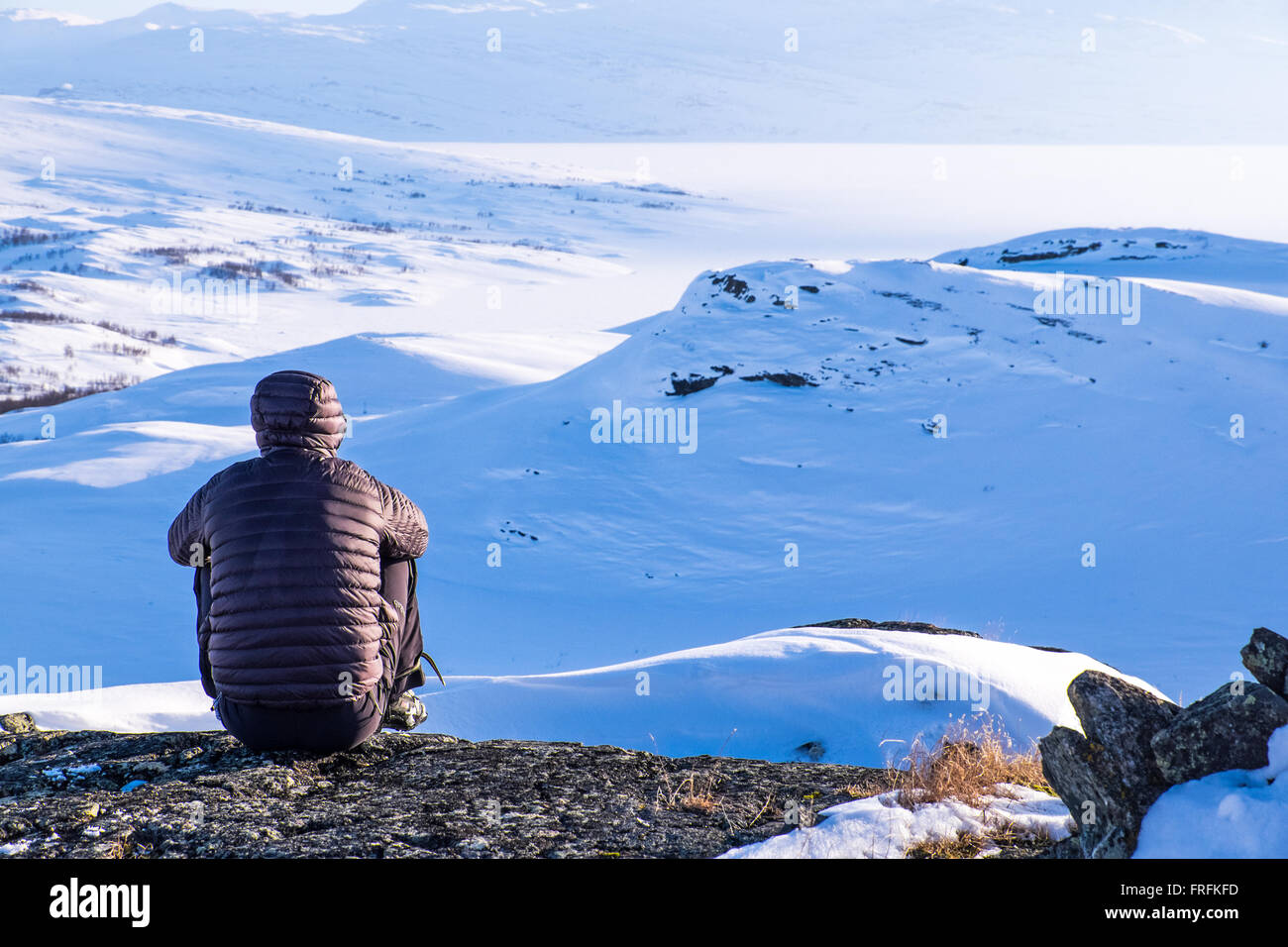 Person im Bergsport Kleidung sitzt betrachten Junkerdal Nationalpark in Norwegen Stockfoto