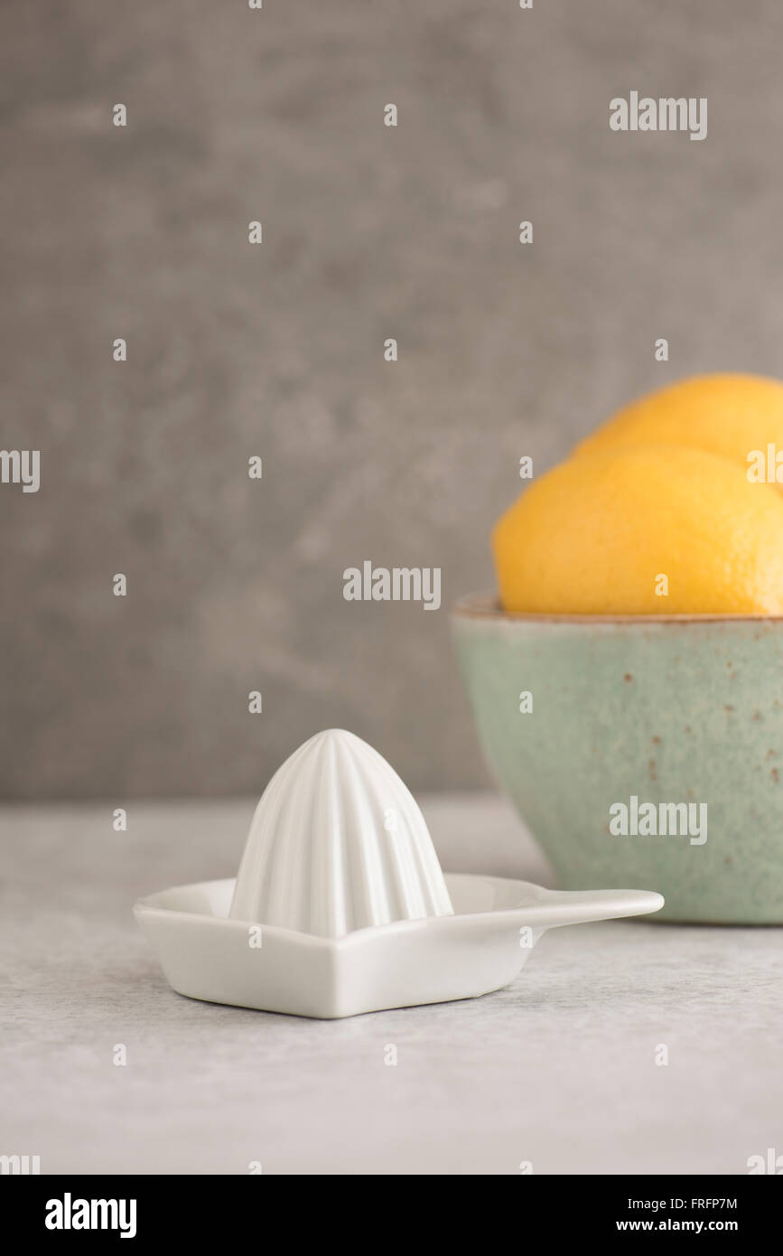 Zitronen in eine Schüssel geben und die Saftpresse am Küchentisch. Obst-Stilleben. Stockfoto
