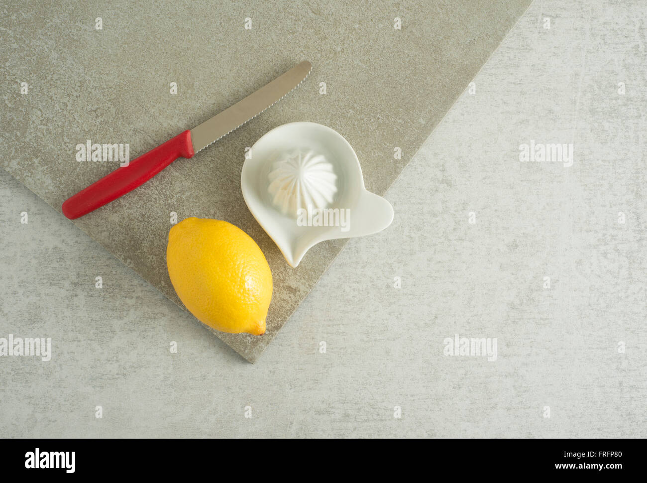 Zitrone, Messer und Saftpresse am Küchentisch. Konzept der Zubereitung von Speisen und Kochen mit frischen Früchten. Stockfoto
