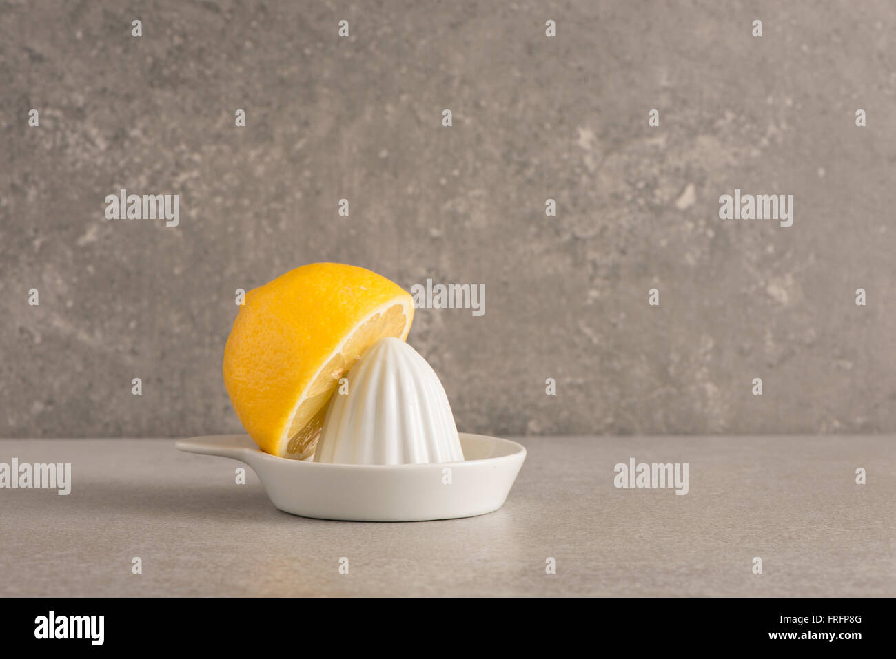 Zitrone und Saftpresse am Küchentisch. Obst-Stilleben. Stockfoto