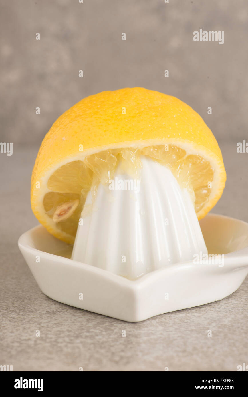 Zitrone und Saftpresse am Küchentisch. Konzept der Zubereitung von Speisen und Kochen mit frischen Früchten. Stockfoto